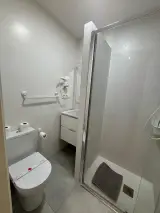 Secador de pelo de pared sobre el lavabo del baño con el espejo y la barra portatoallas a un lado